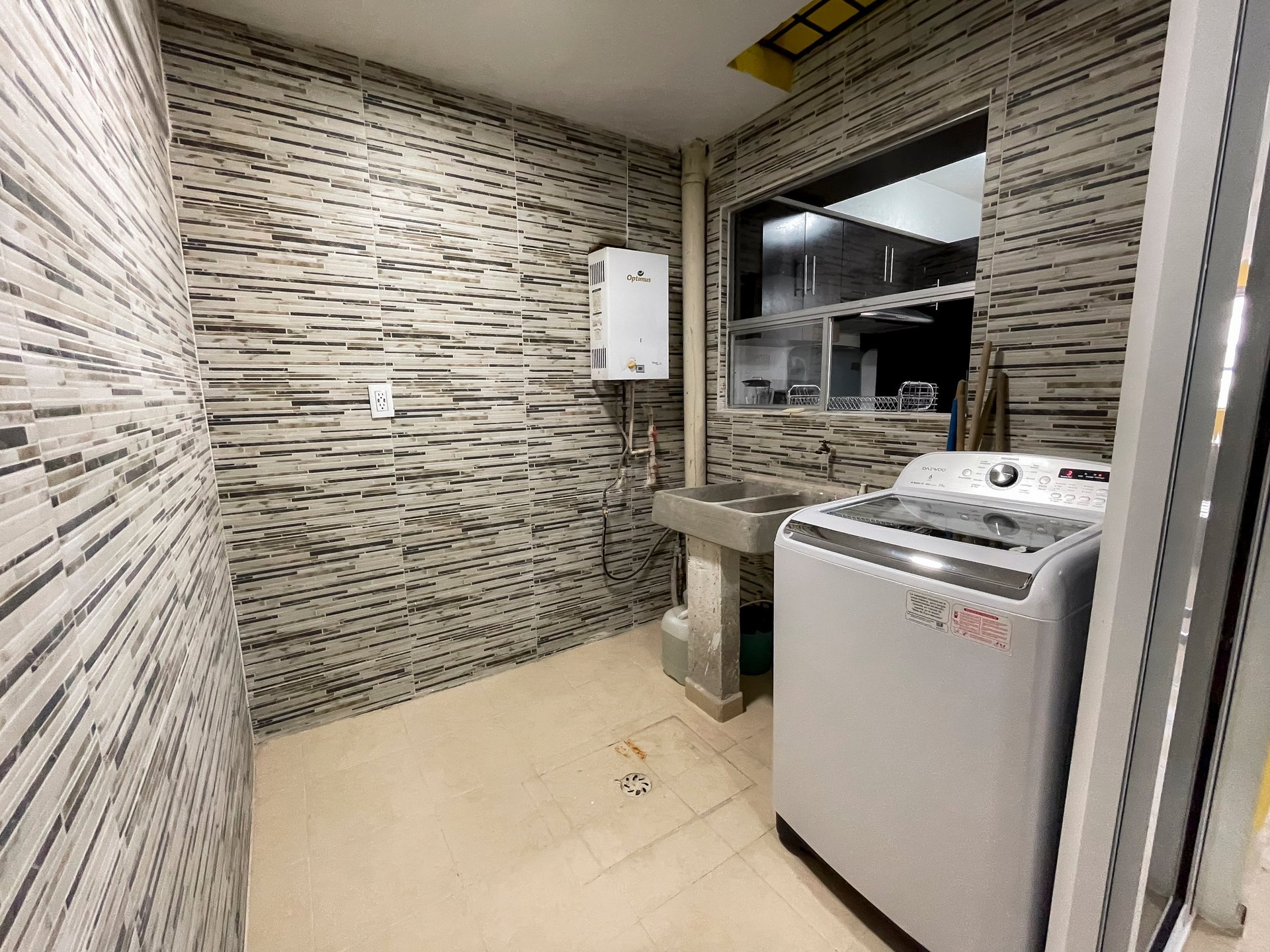Modern laundry room with striped tile walls, white washing machine, water heater, and mirror
