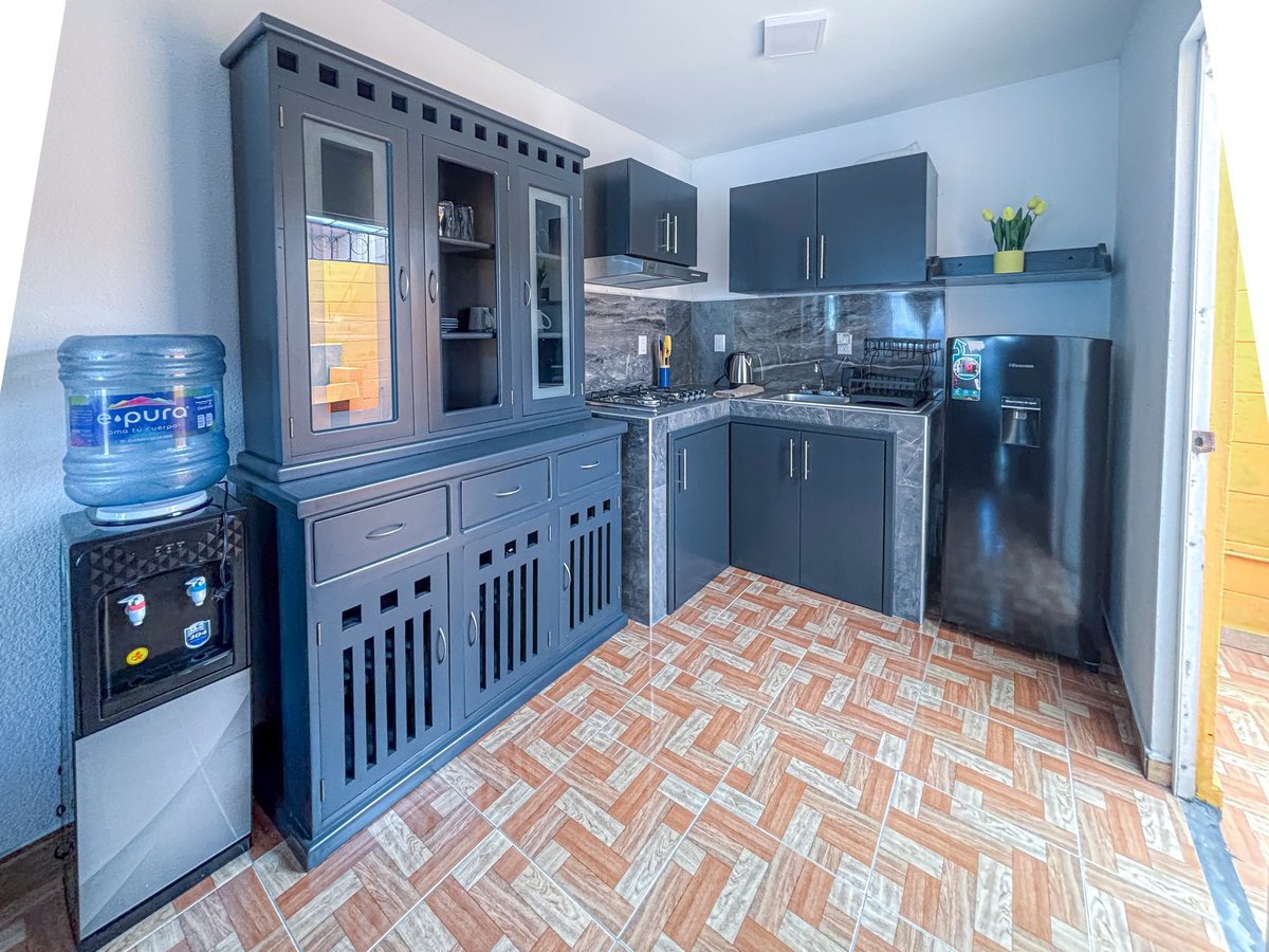 Modern kitchen with dark blue cabinetry, stainless steel appliances, brick-patterned flooring, and water cooler.