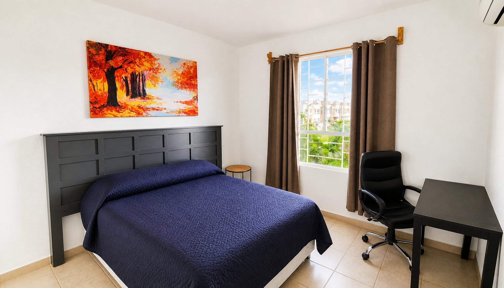 Modern bedroom with dark headboard bed, blue bedding, warm landscape art, window with curtains, and workspace desk.