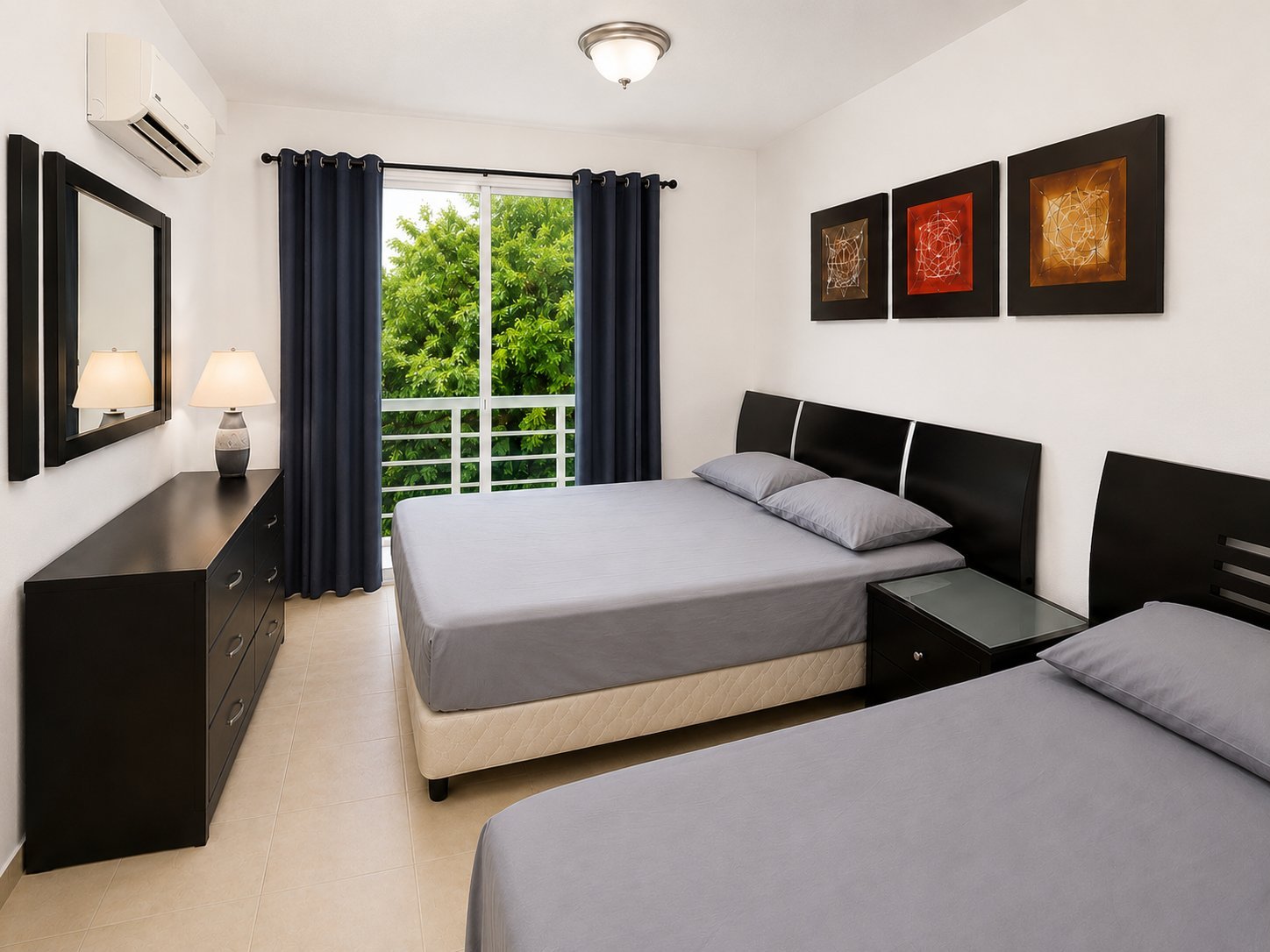 Modern bedroom with two beds, black headboards, gray bedding, dark curtains, balcony doors, and abstract wall art