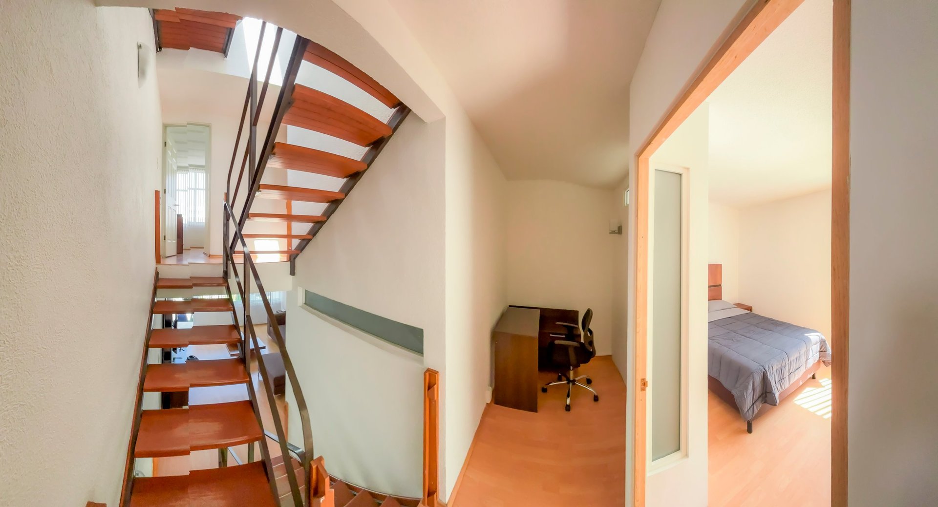 Interior hallway with staircase, leading to bedroom and office spaces in residential home
