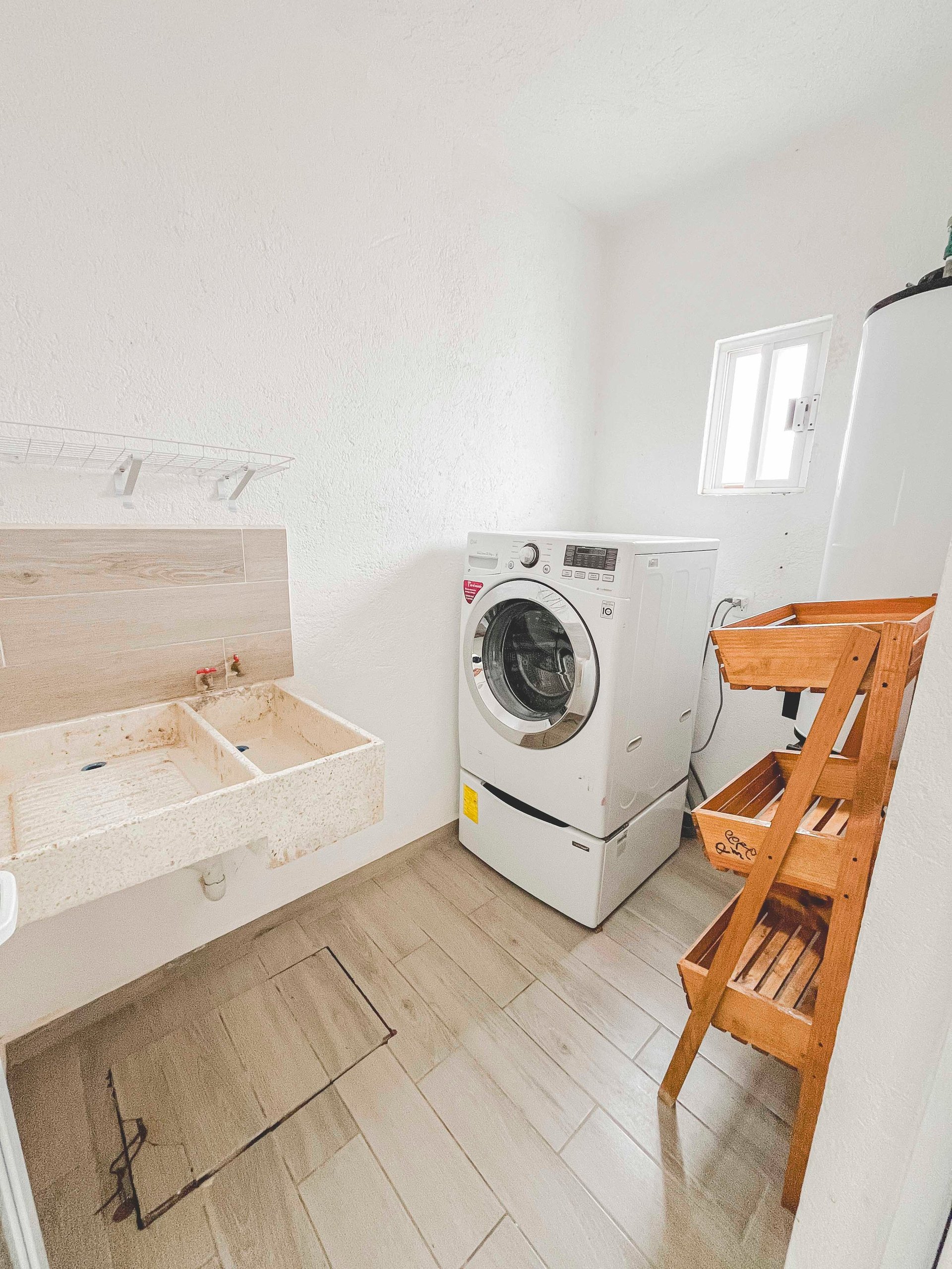 A bright laundry room with wooden storage cabinets on the left, a white washing machine in the center, and wooden shelving on the right